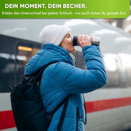Person drinks from a thermobecher at a train station, showcasing portability and insulation for coffee and tea.